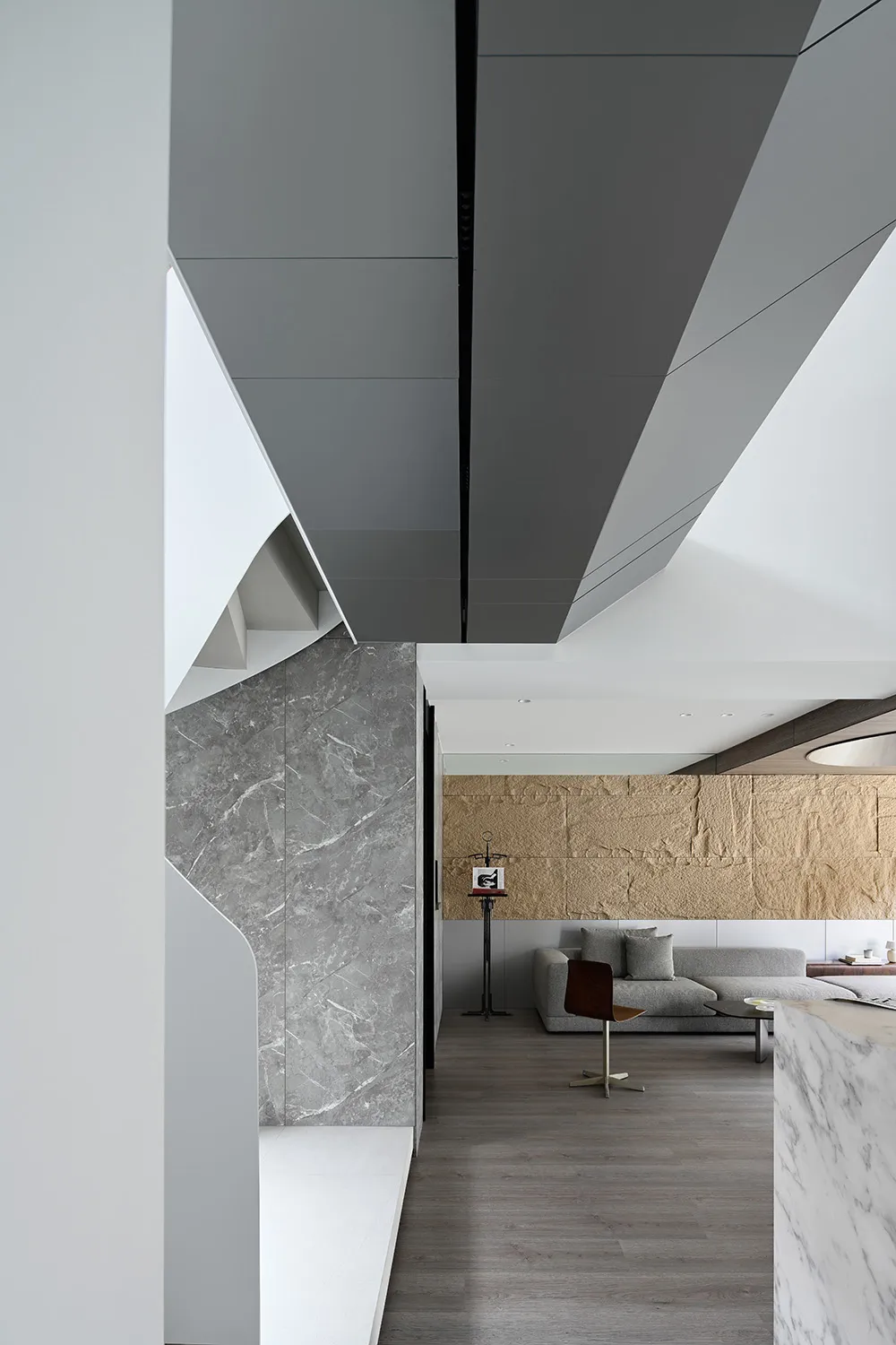 Minimalist living room with grey marble walls and floor, concrete ceiling, and wooden furniture.