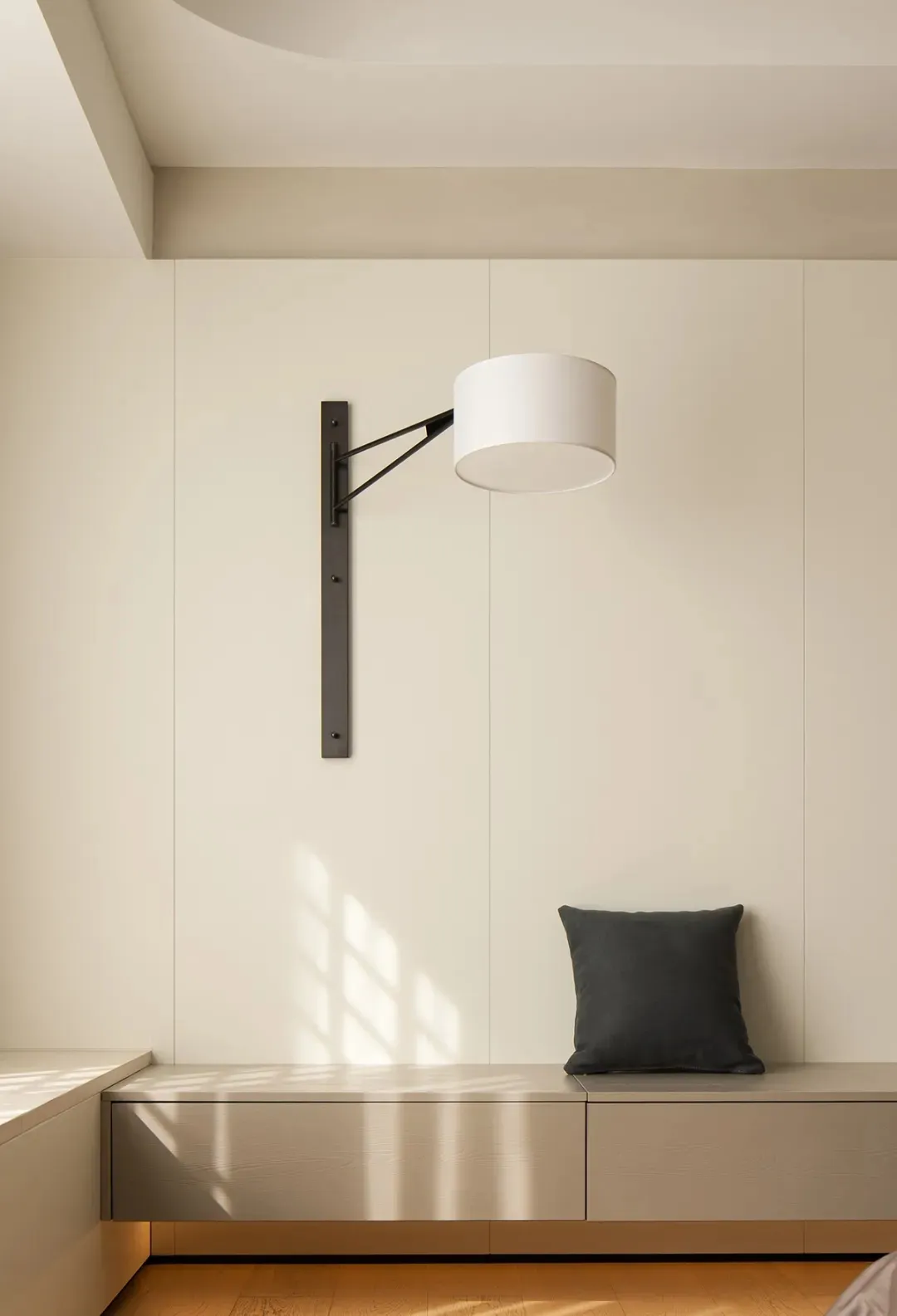 Modern minimalist bedroom with white furniture, wooden floor, and light fixture