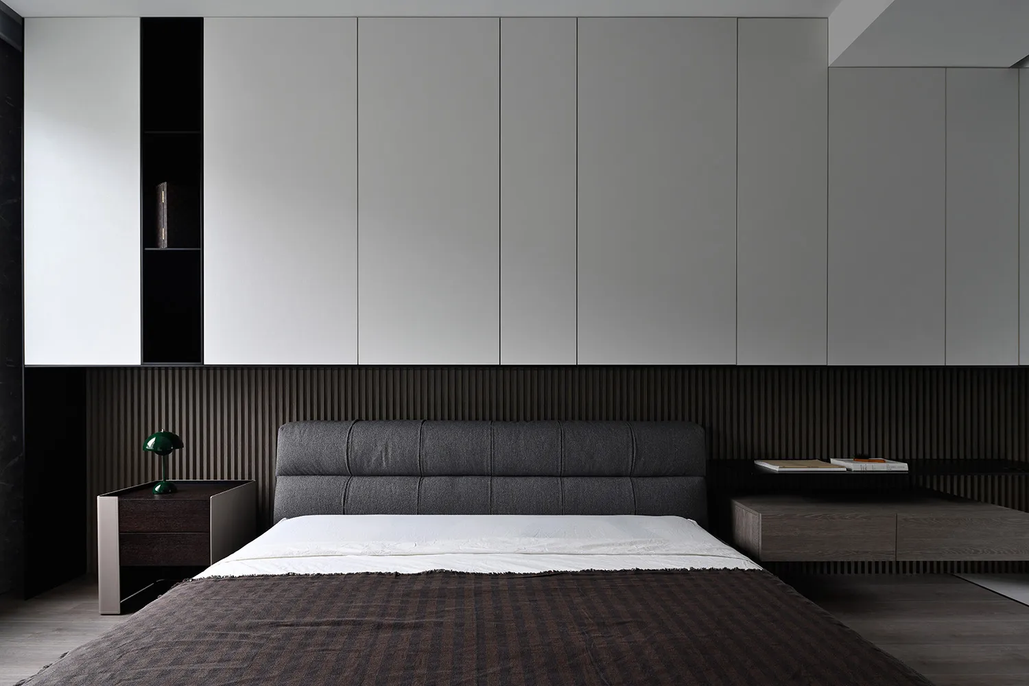 A modern bedroom featuring a bed with textured fabric headboard and wooden floor.