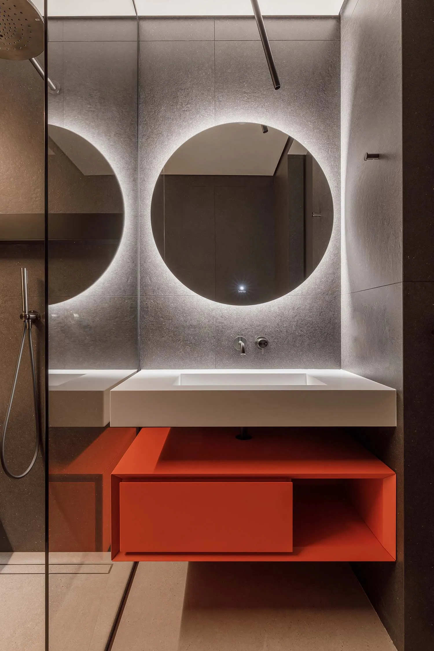 A modern bathroom featuring a sleek, minimalist design with concrete walls and a circular mirror.