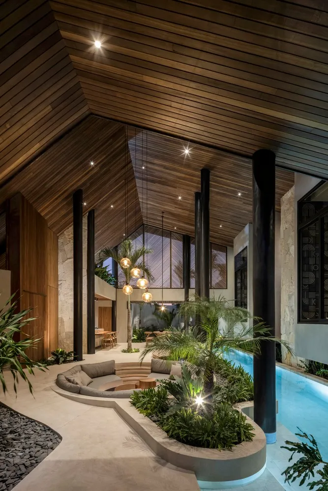 Modern living room with wood ceilings, concrete seating area, and glass walls.