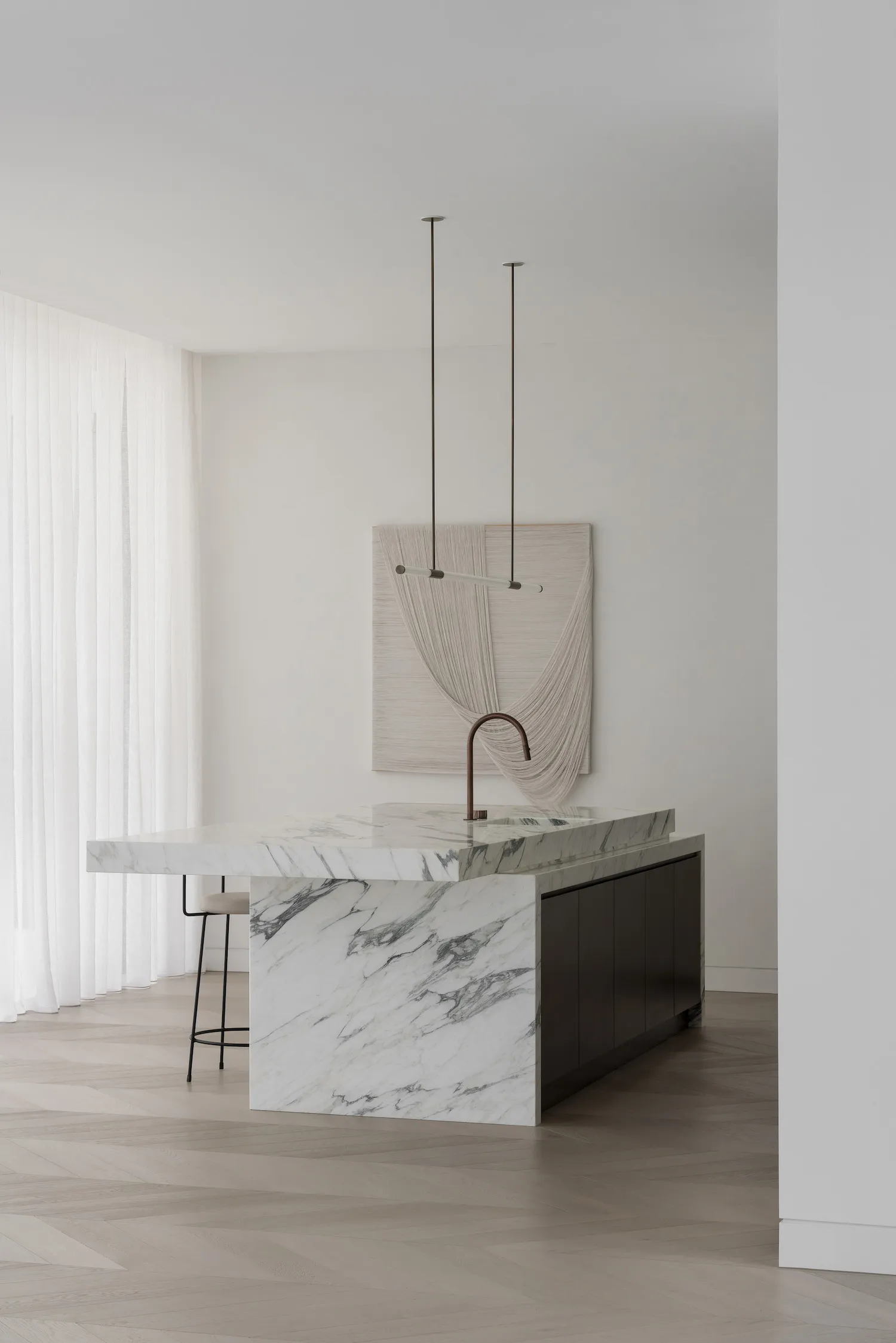 Modern kitchen with white marble countertops and black cabinetry.