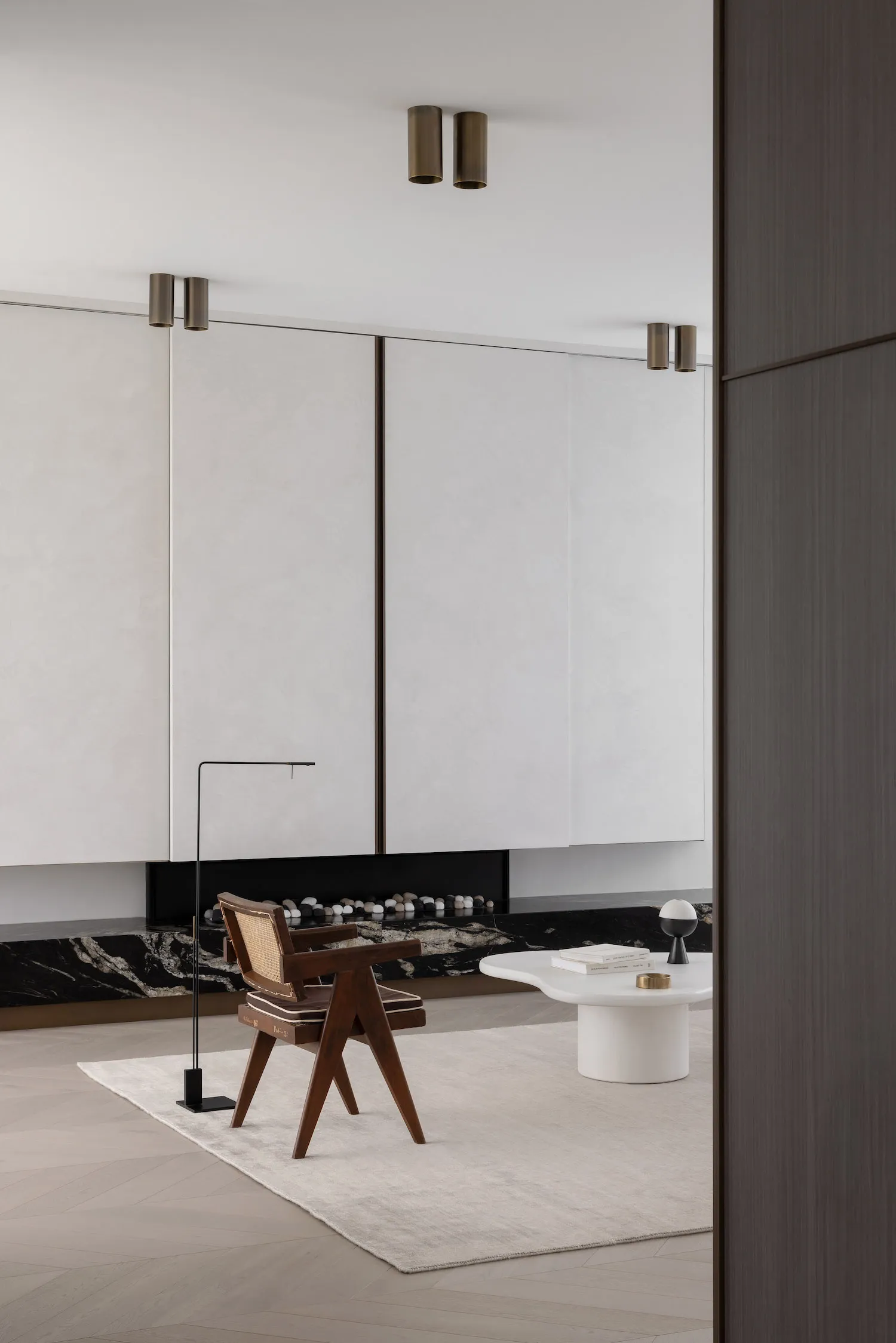 Modern minimalist living room featuring white walls, dark wood accents, and marble surfaces.