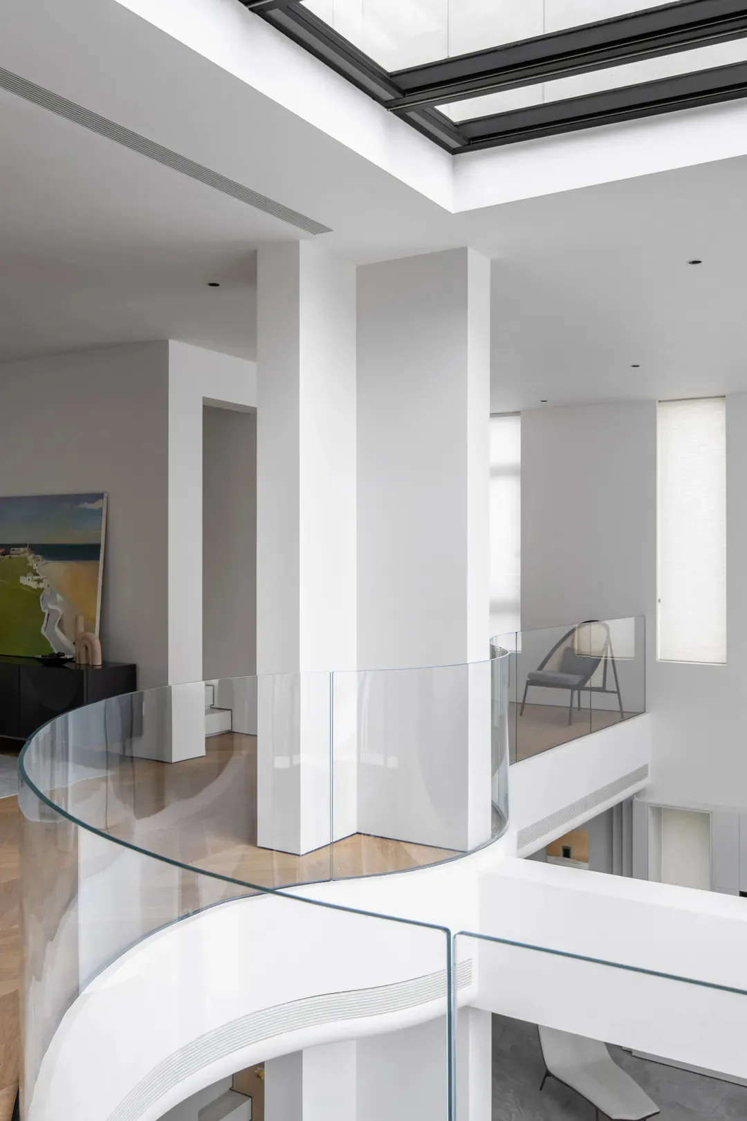Modern residential interior design featuring glass railings and white walls.