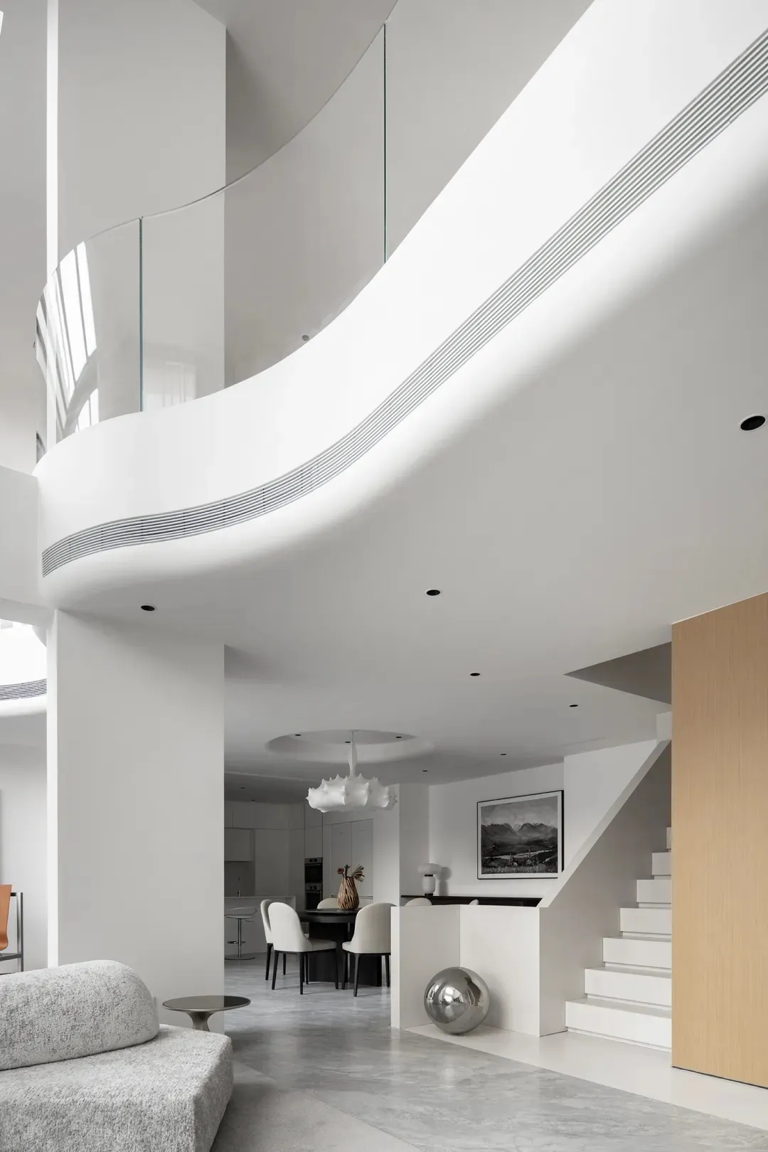 Modern living room with white walls, concrete floor, glass balustrades, and minimalist furniture.