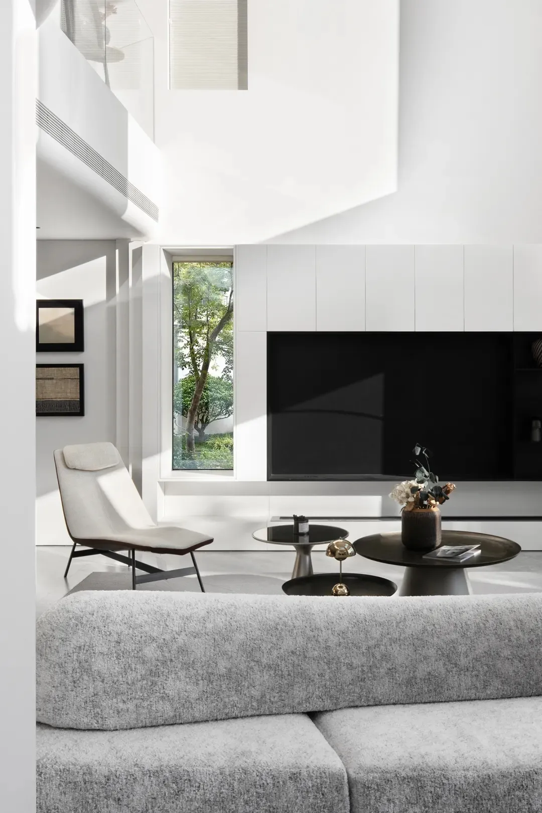 A modern minimalist living room with light-colored furniture, a sleek black entertainment center, and a neutral color palette
