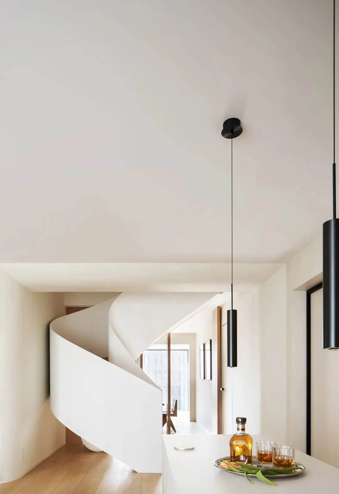 A minimalist interior featuring a white concrete spiral staircase