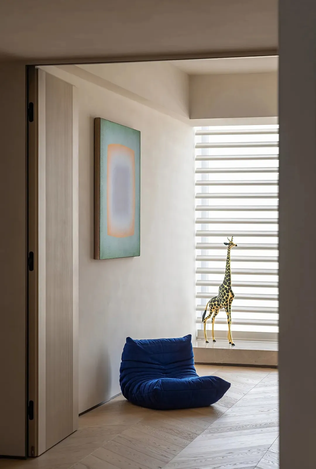 A modern contemporary interior space featuring a contemporary chair, neutral-toned walls, and a giraffe statue.
