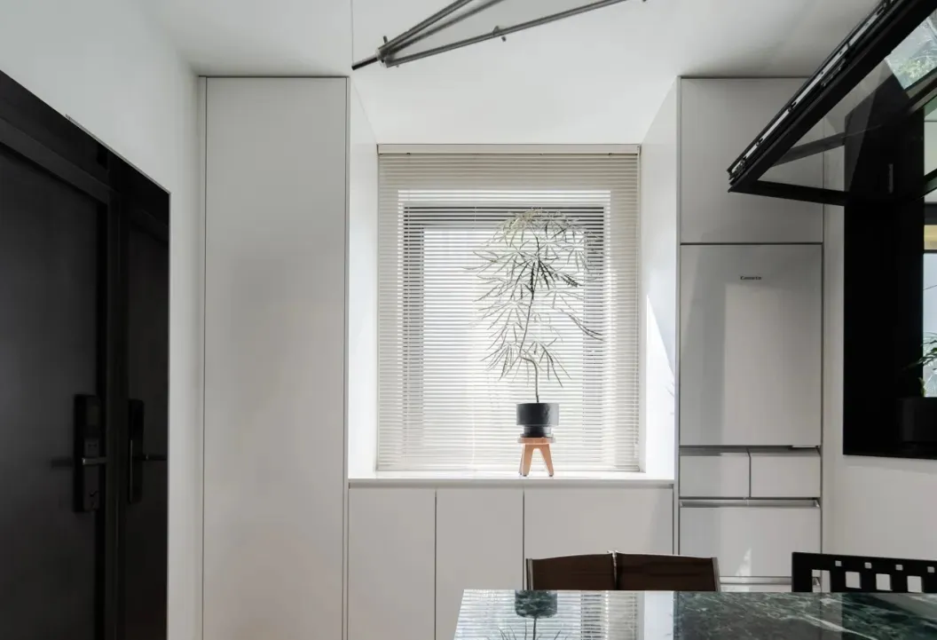A minimalist kitchen featuring a plant on the windowsill and modern design elements.