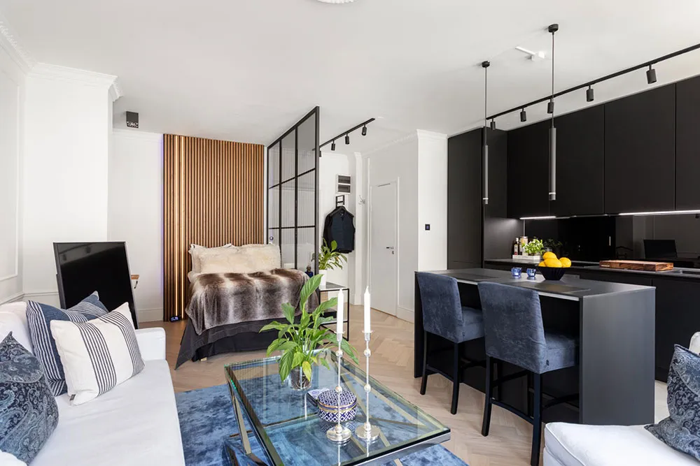 A modern apartment interior featuring a stylish living room with a wood accent wall and a well-designed kitchen area.