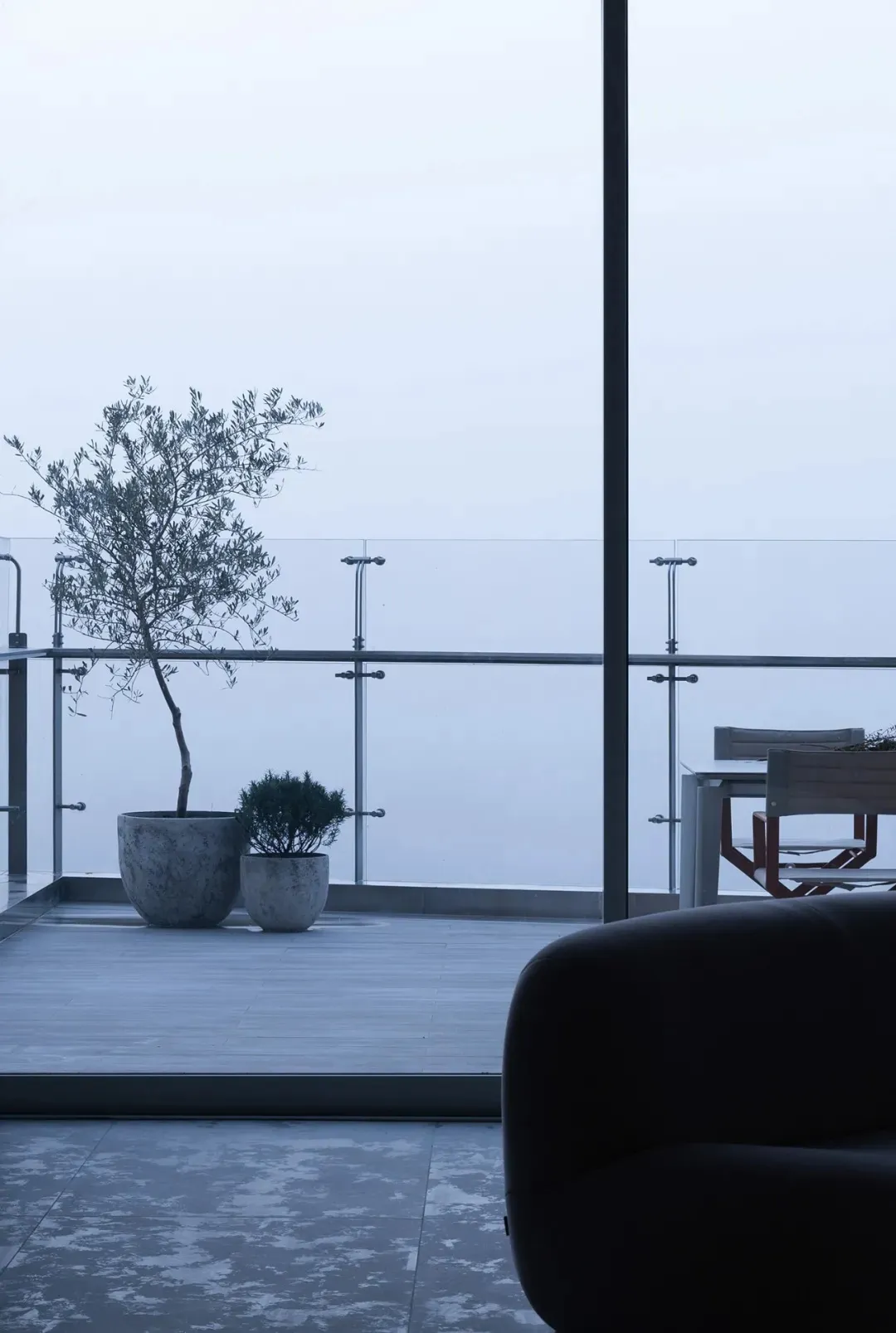 A modern living room featuring concrete and glass materials with a minimalist design.