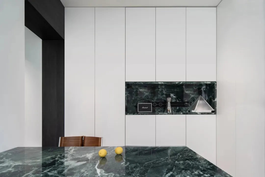 Modern kitchen featuring green marble countertops and white cabinets