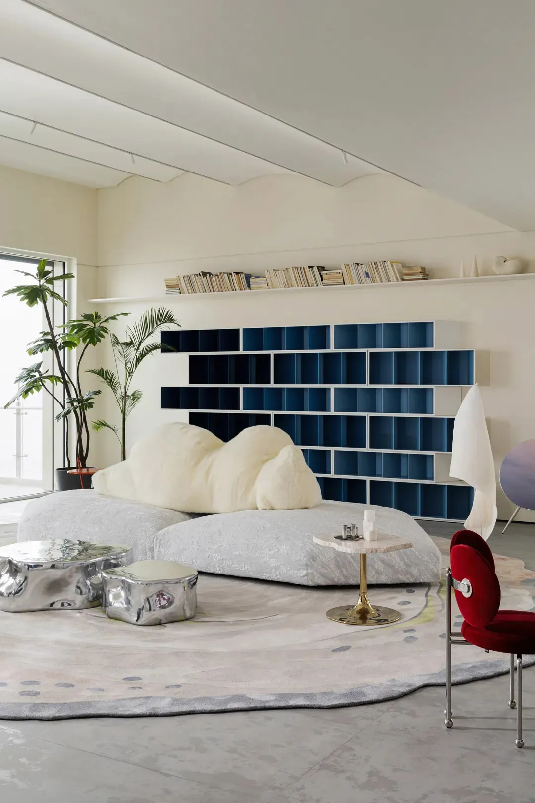 A modern living room featuring plush textiles, metallic furniture, and glass elements.