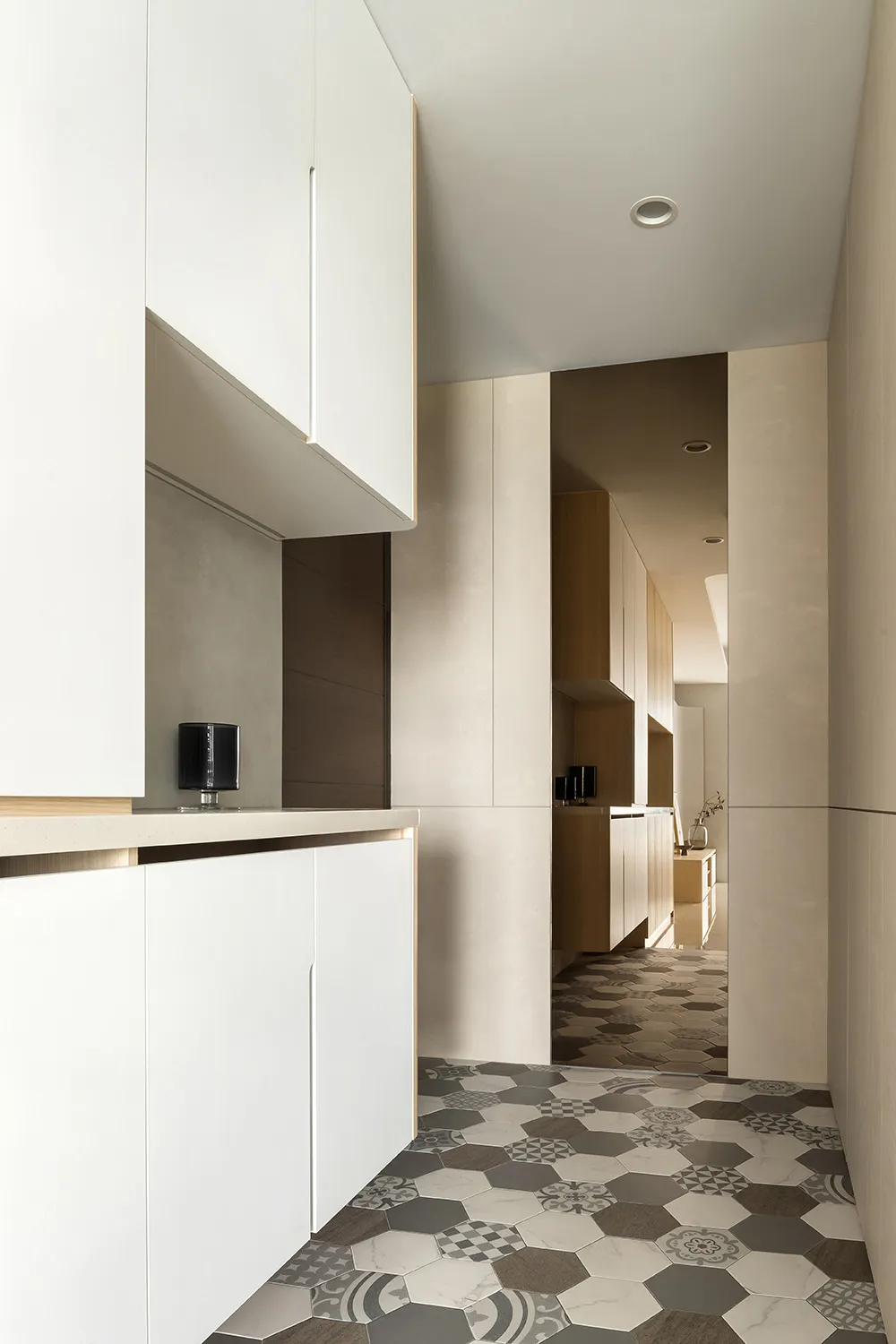 Modern residential kitchen with minimalist design, white cabinets, and marble walls