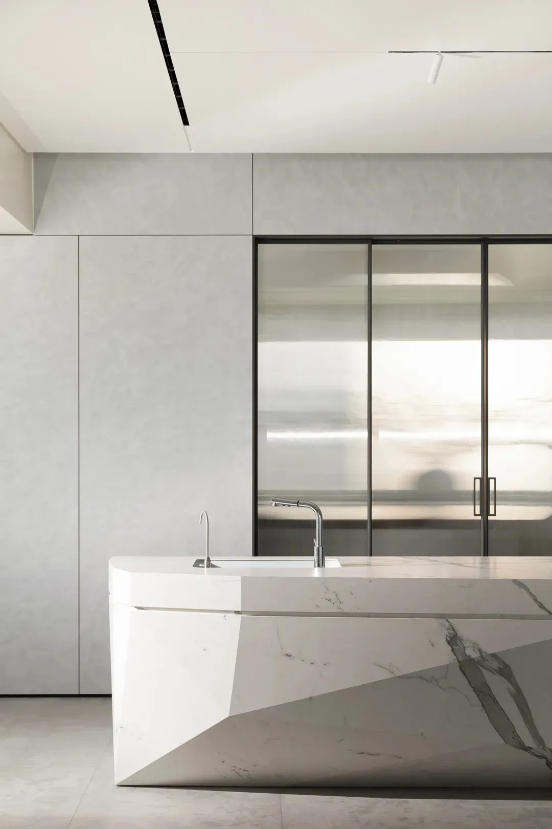 A modern kitchen with white marble countertops and sleek, minimalist design.