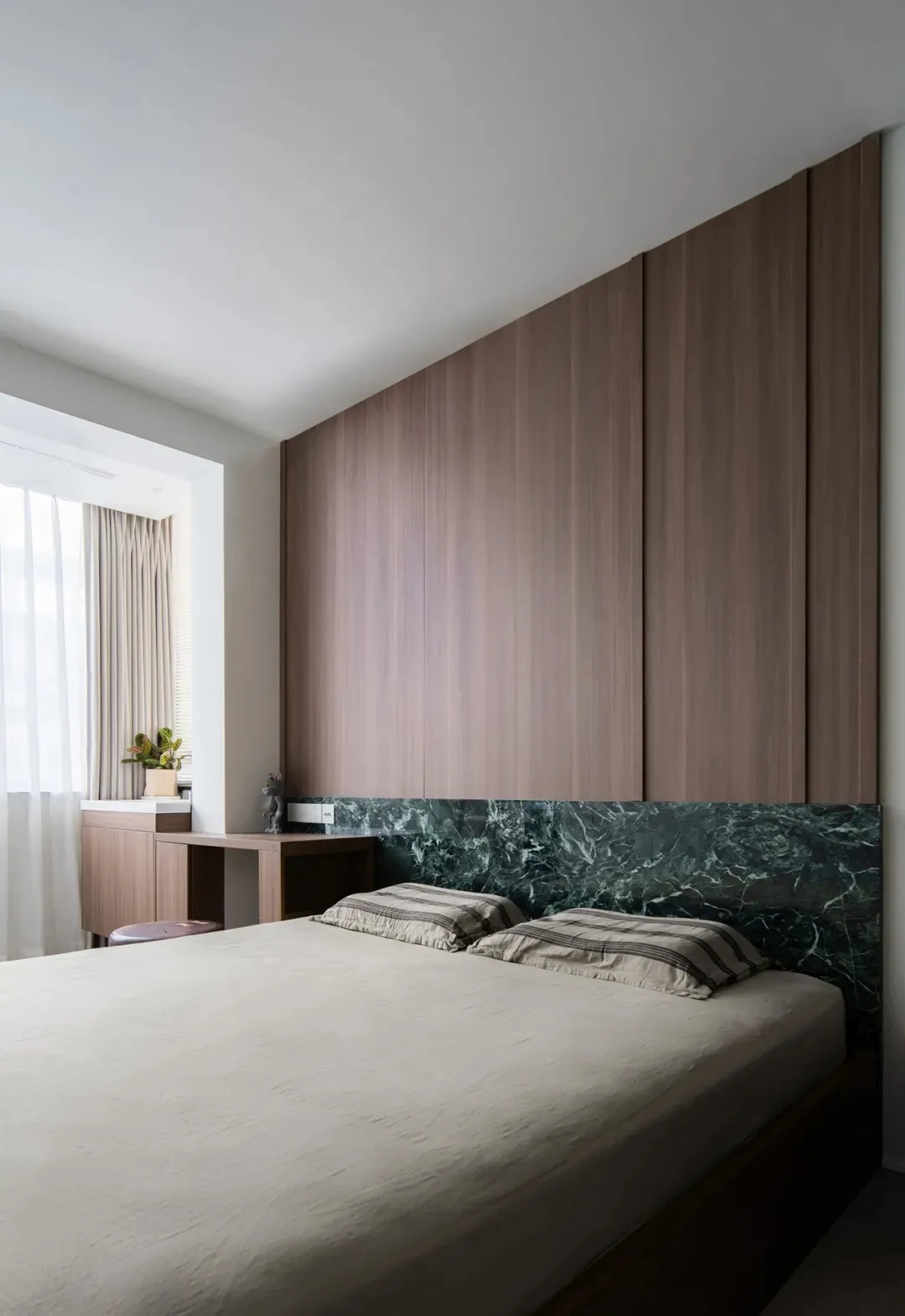 A modern minimalist bedroom with wood paneling and a marble headboard.