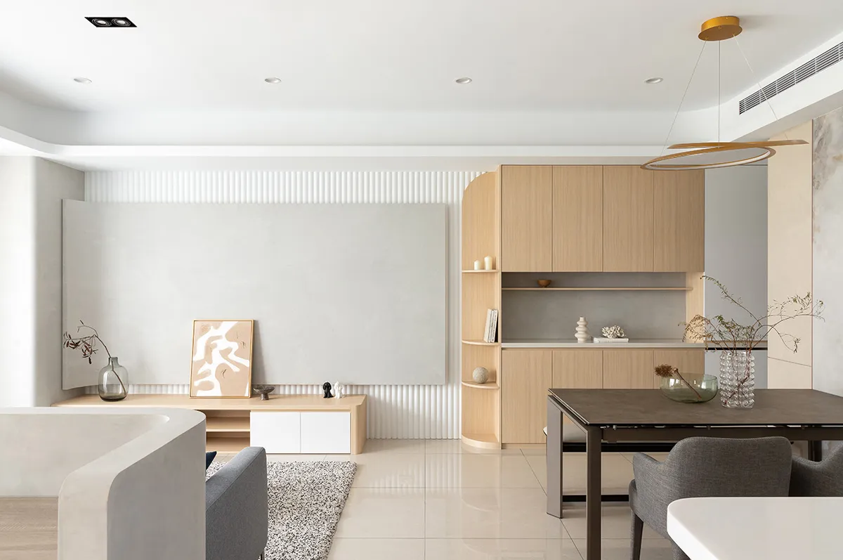 Modern minimalist living room with wooden furniture, a large blank wall, and a white floor.