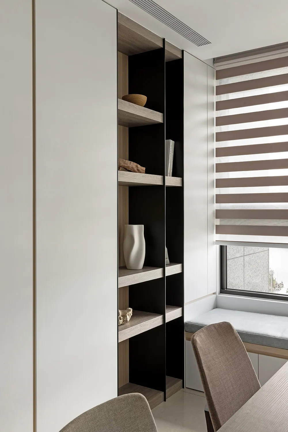 A modern bookshelf with wooden shelves, featuring decorative items such as a vase and books.