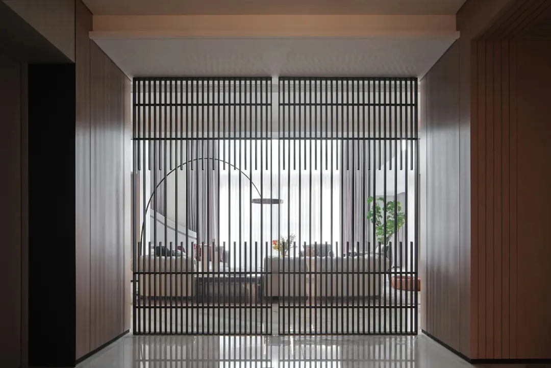 Modern interior design featuring a metal door with vertical bars and a curved handle.