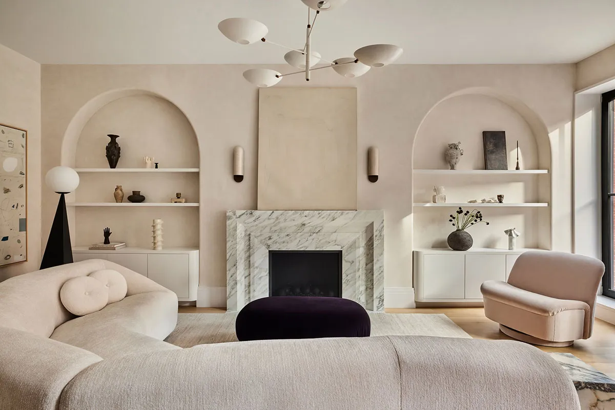 A modern minimalist living room with a concrete fireplace and floating shelves.