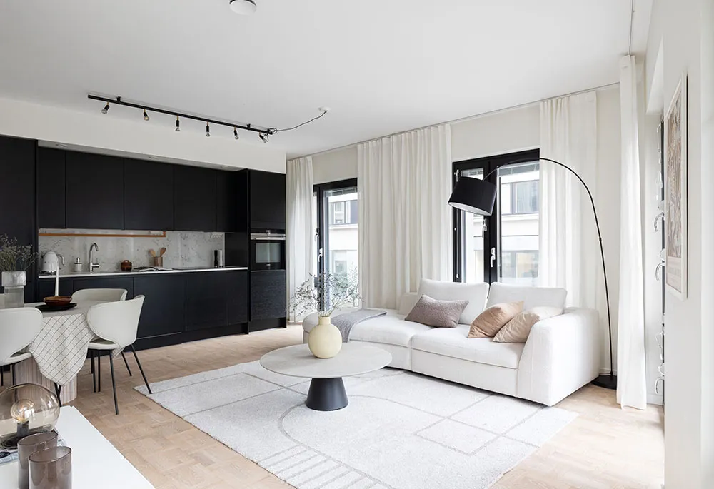 A modern living room with neutral-toned furniture, minimalist decor, and a white rug on a wooden floor.
