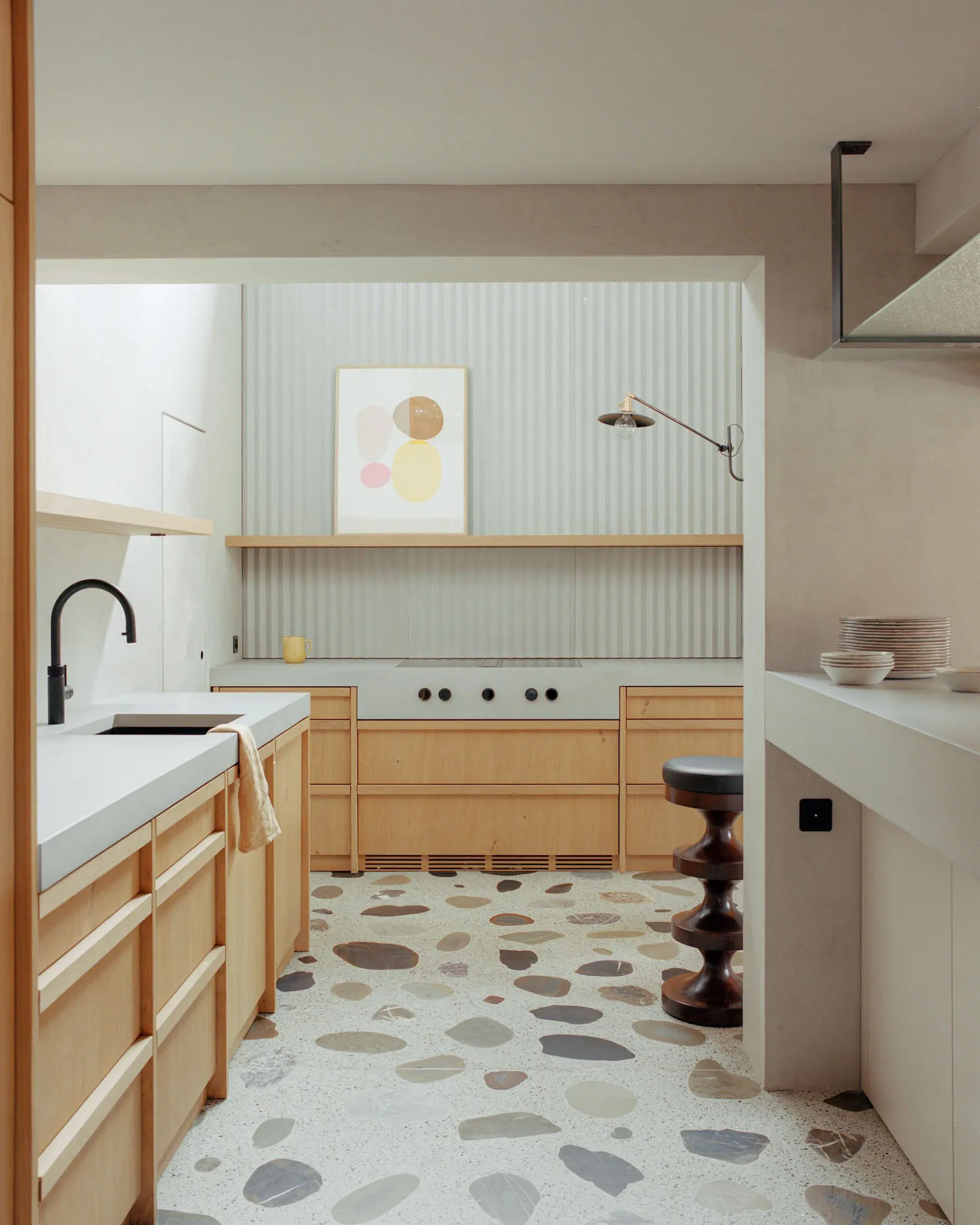 A minimalist kitchen with a terrazzo tiled floor and light wooden cabinets.