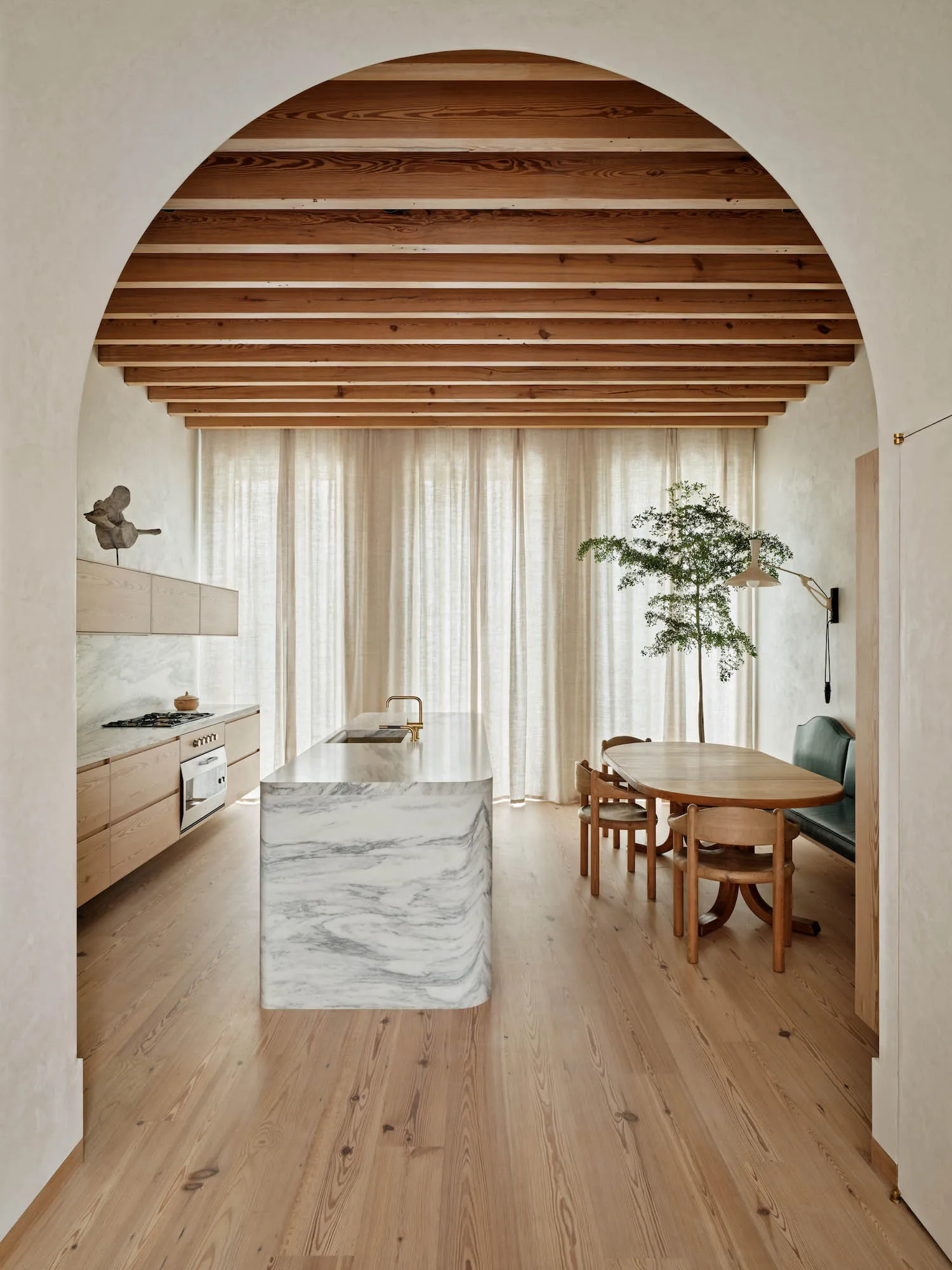 Modern residential kitchen featuring a marble countertop, wooden cabinets, and fabric curtains.