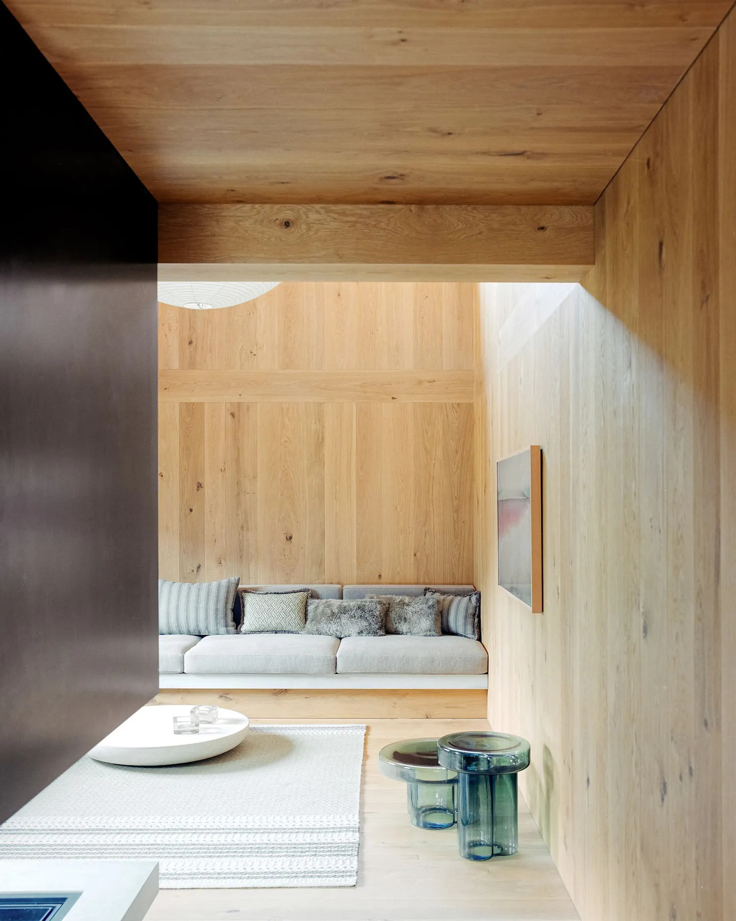 A modern living room with a wooden accent wall and built-in seating area.