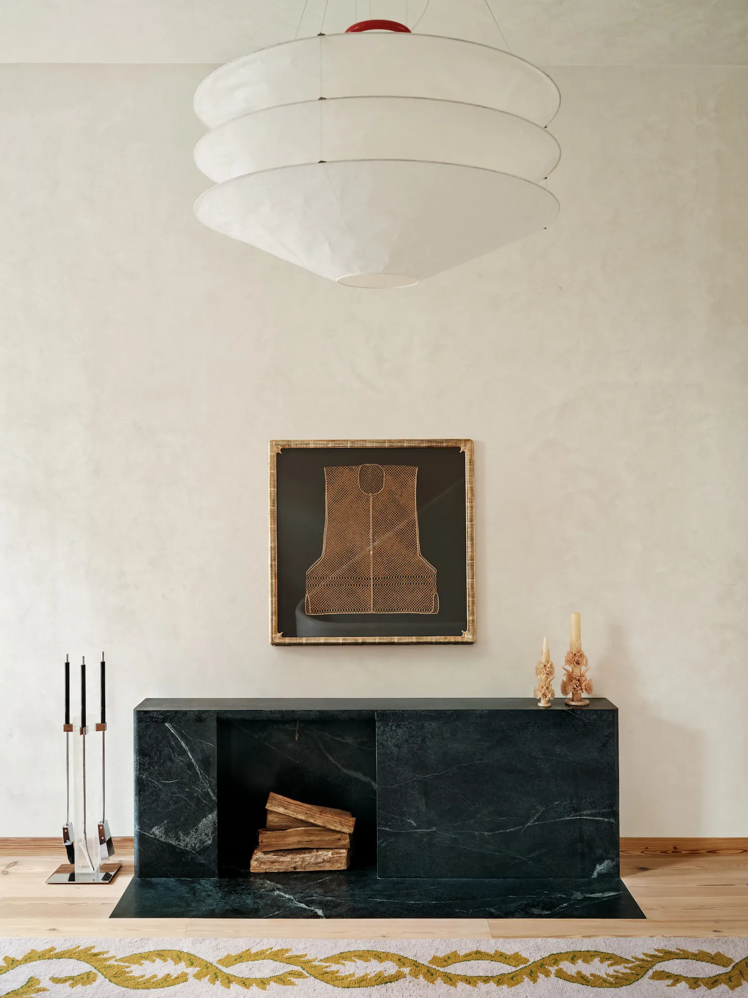 Modern living room decorated with a black marble fireplace and a pendant light with stacked white circular shades.