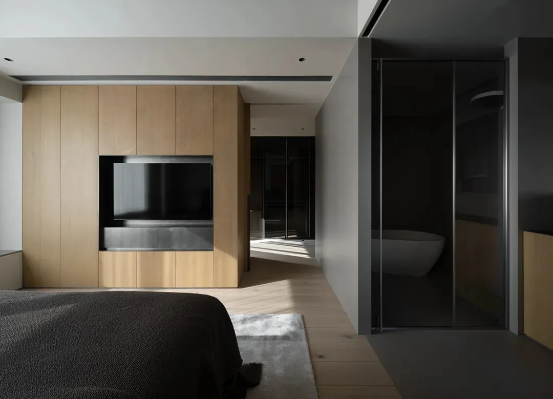 A modern minimalist bedroom featuring dark wood accents, glass panels, and concrete flooring.
