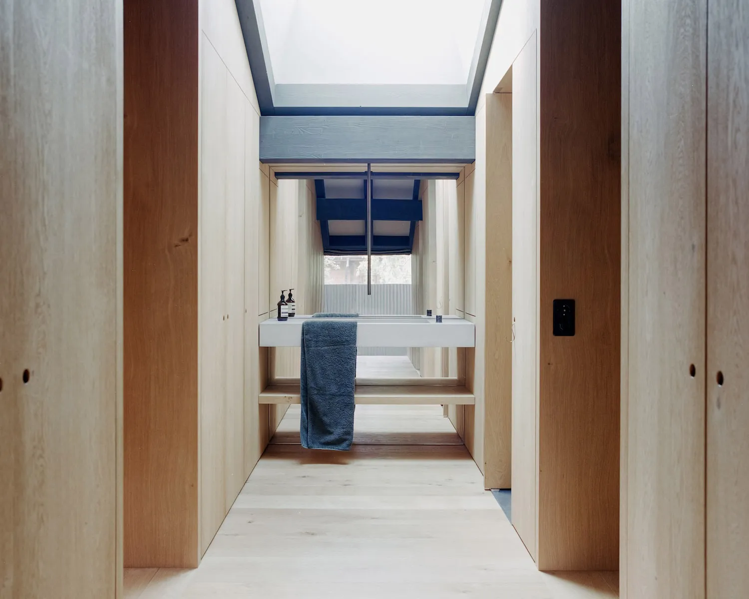Modern bathroom interior with wooden walls, skylights, and white fixtures