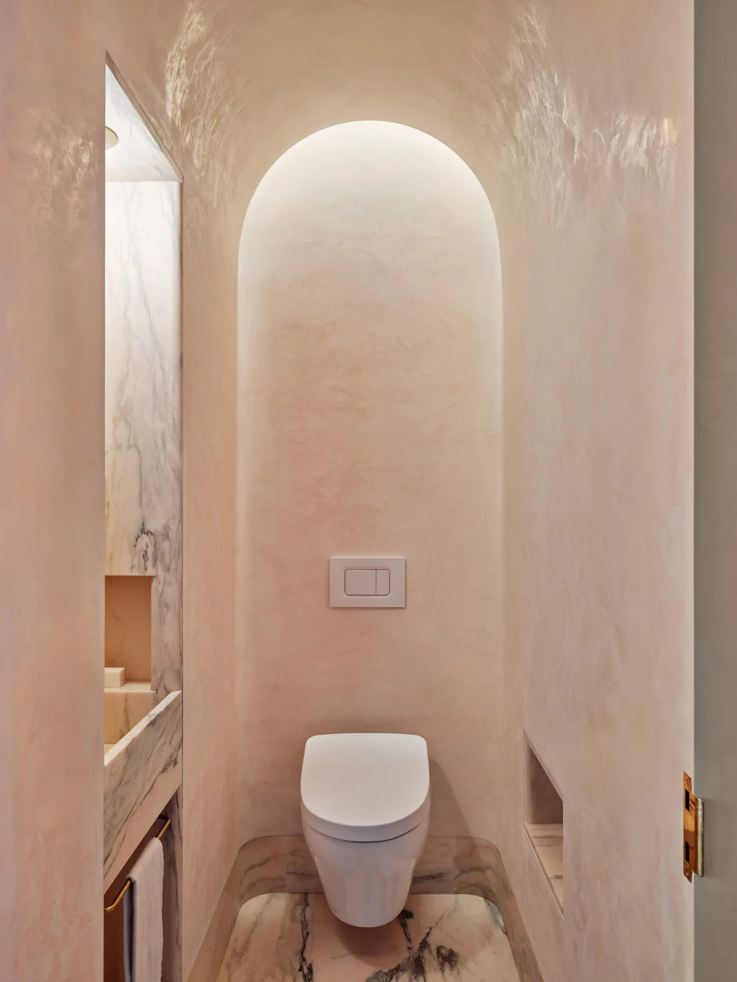 A modern bathroom with marble finishes and an arched doorway.