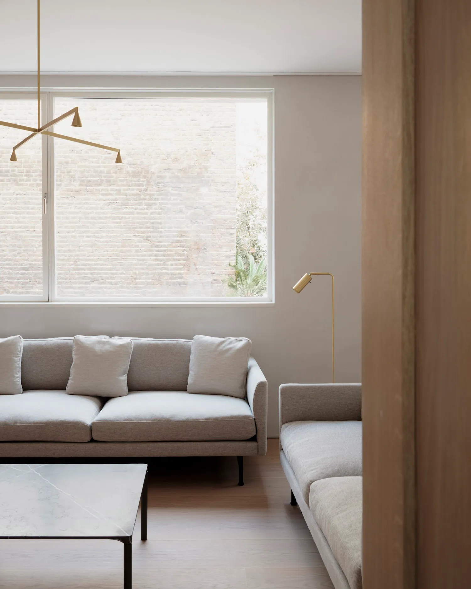 A modern minimalist living room with gray fabric sofas, a marble coffee table, and a floor lamp.