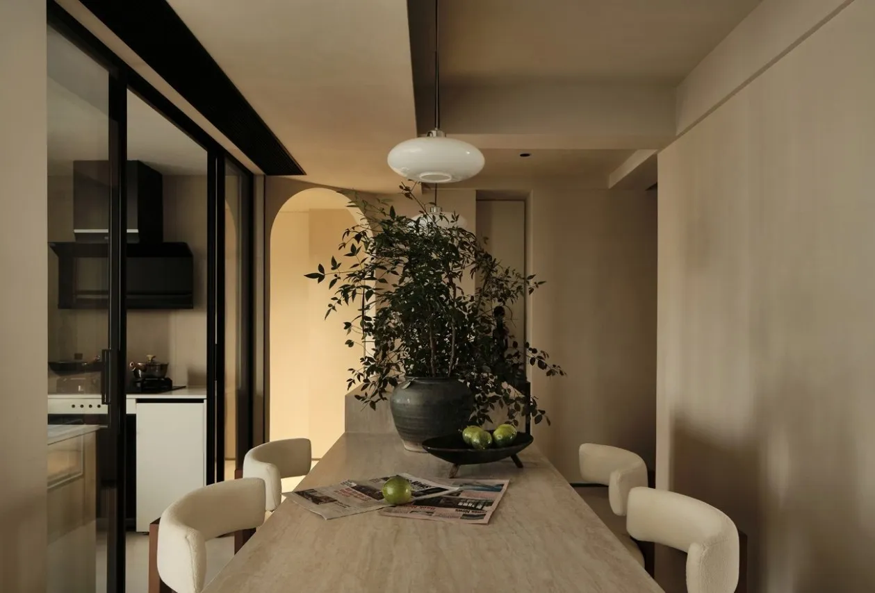 Marble dining table with chairs, plants, and a bowl of green fruits in a modern interior setting.