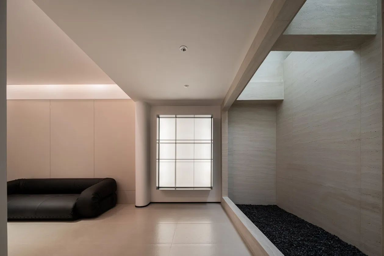 Minimalist living space featuring concrete walls and large glass windows.