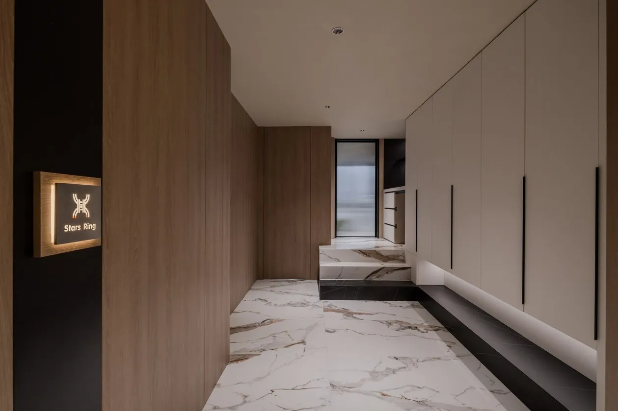 Modern entrance corridor with marble flooring and wooden walls.