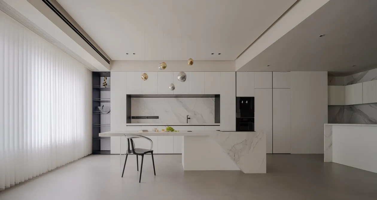 A modern residential kitchen featuring marble finishes and minimalist design.