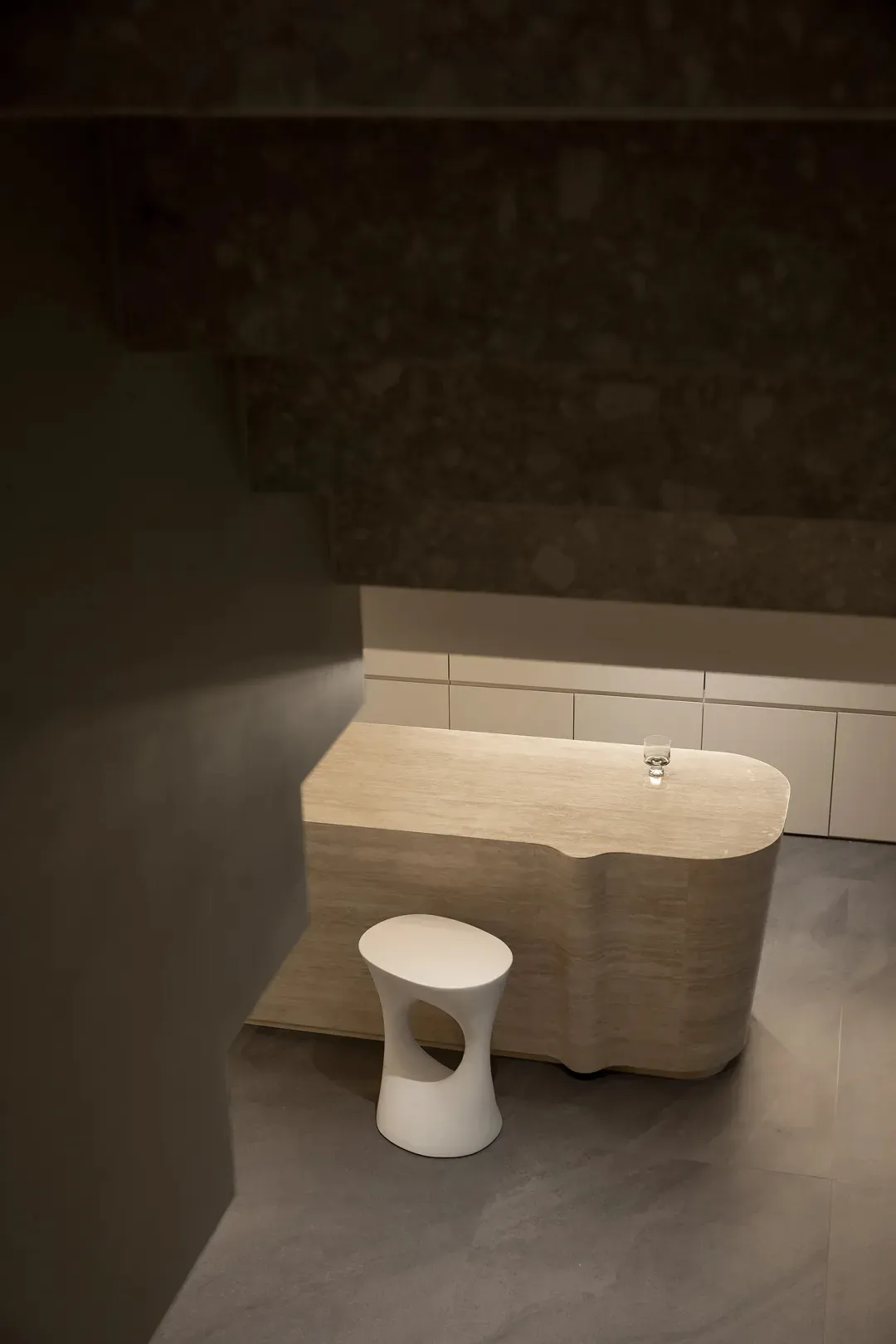 A modern, minimalist furniture set made of sandstone, featuring a sleek, organic-shaped table and a matching stool with a cut