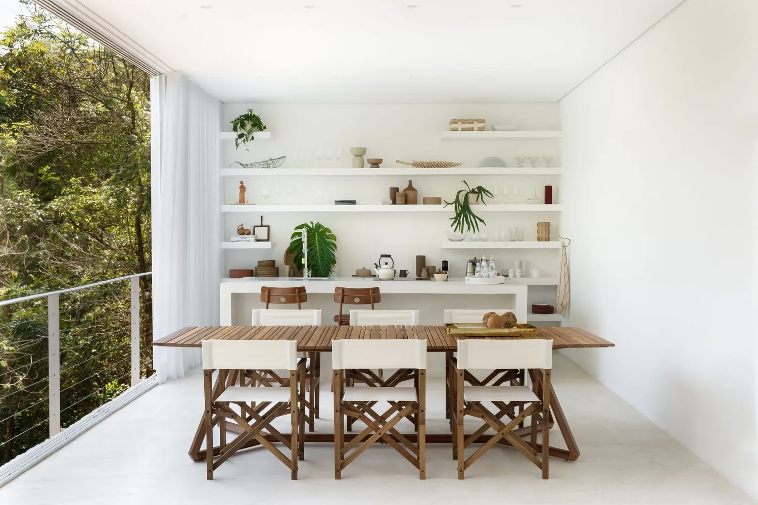 Modern dining room with light wooden table and chairs, ceramic shelving, and green plants
