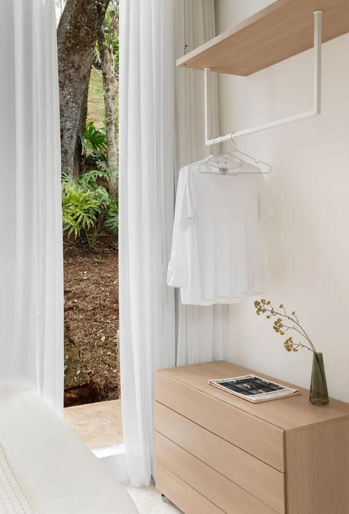A minimalist closet interior featuring white Sherwood wood furniture and a white t-shirt hanging on a white hanger.