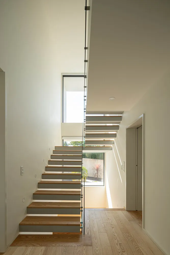 A modern staircase with wooden steps and glass railing.
