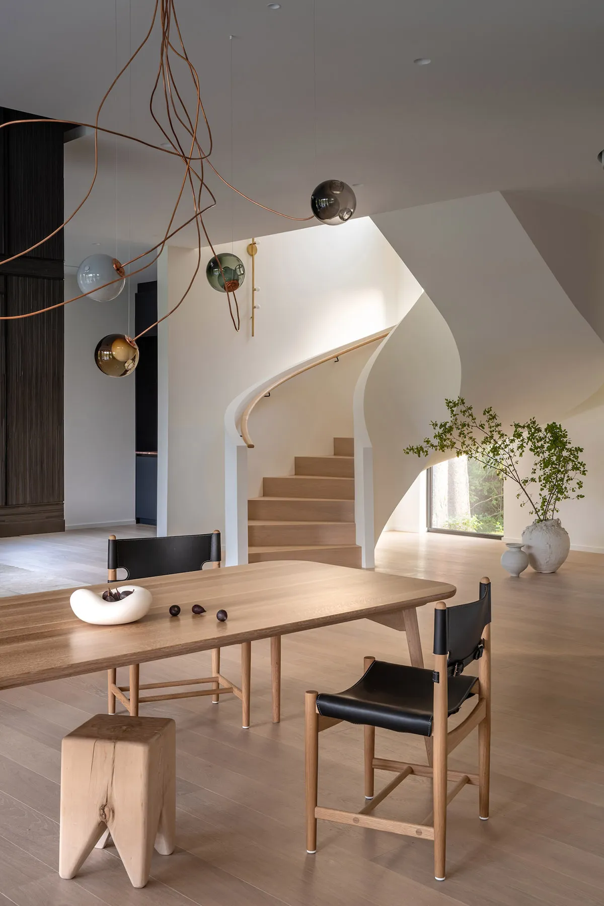 Modern residential dining room featuring wooden dining table and leather chairs.
