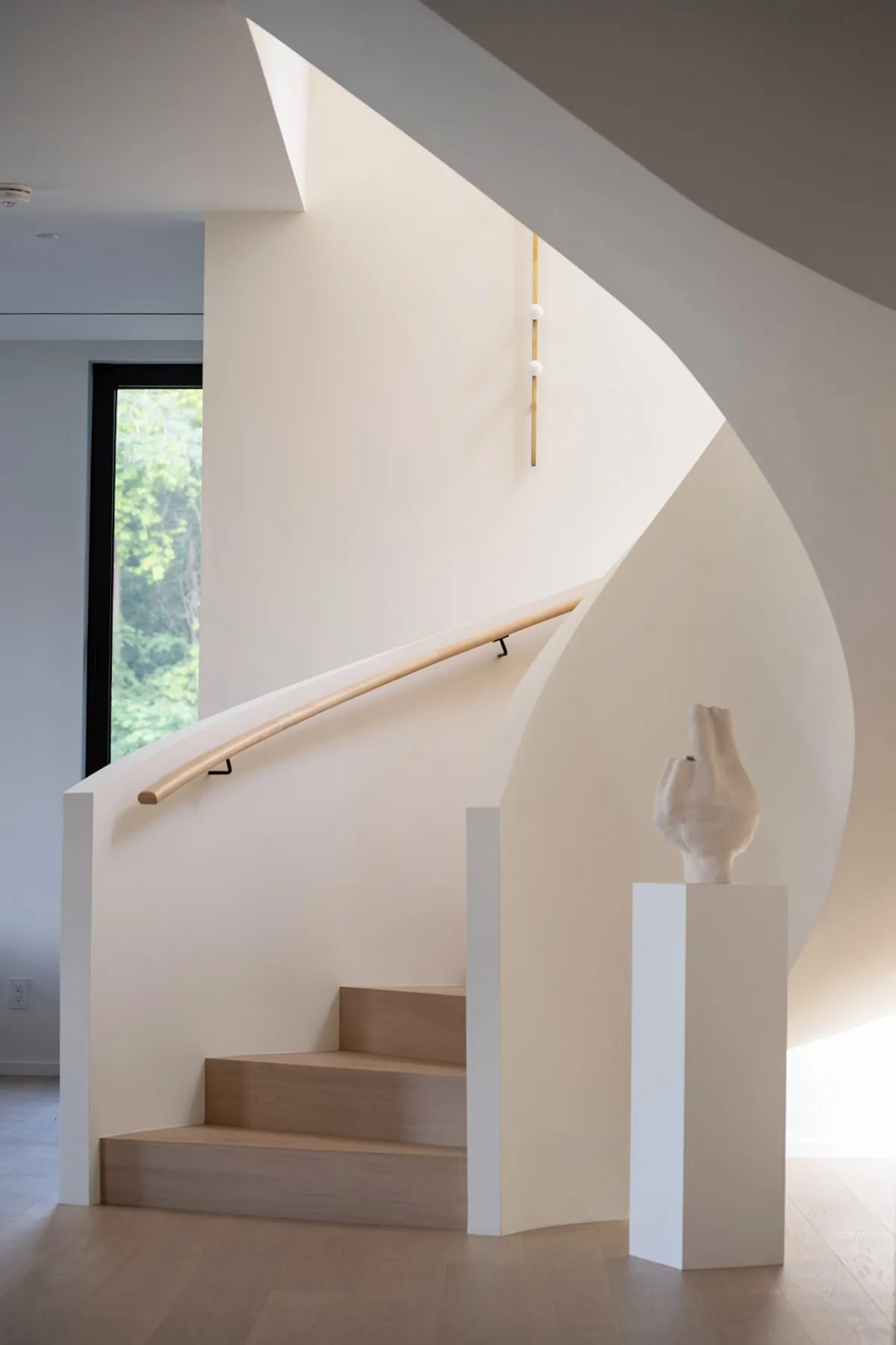 A modern staircase with white walls, wood steps, and a wooden handrail.