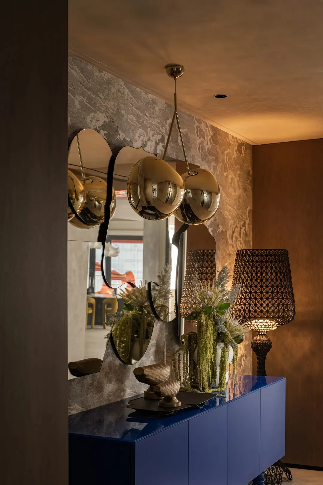 Luxurious metallic entry way with decorative mirrors and lamps.