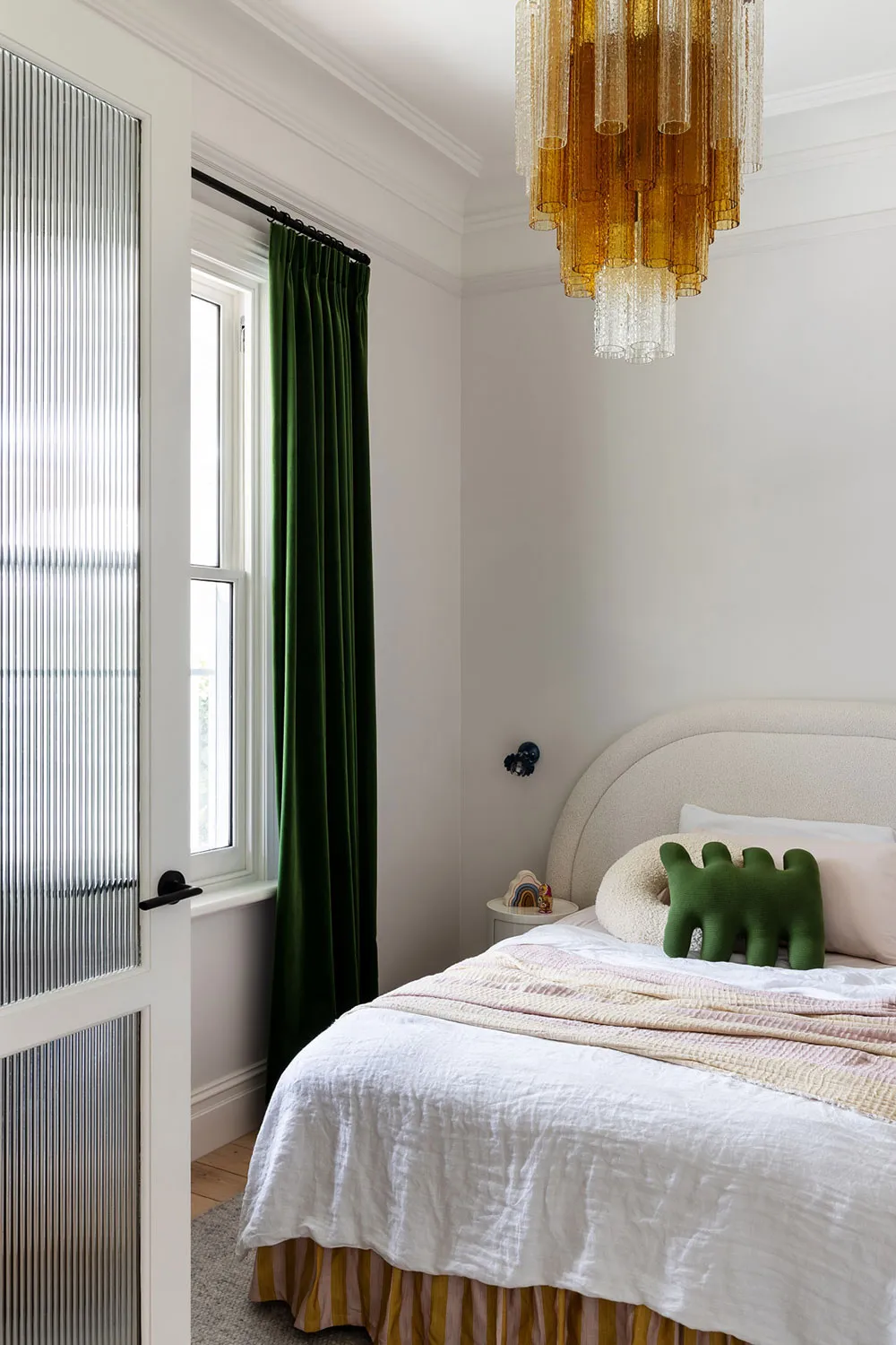 A minimalist bedroom with a bed, window, and chandelier.