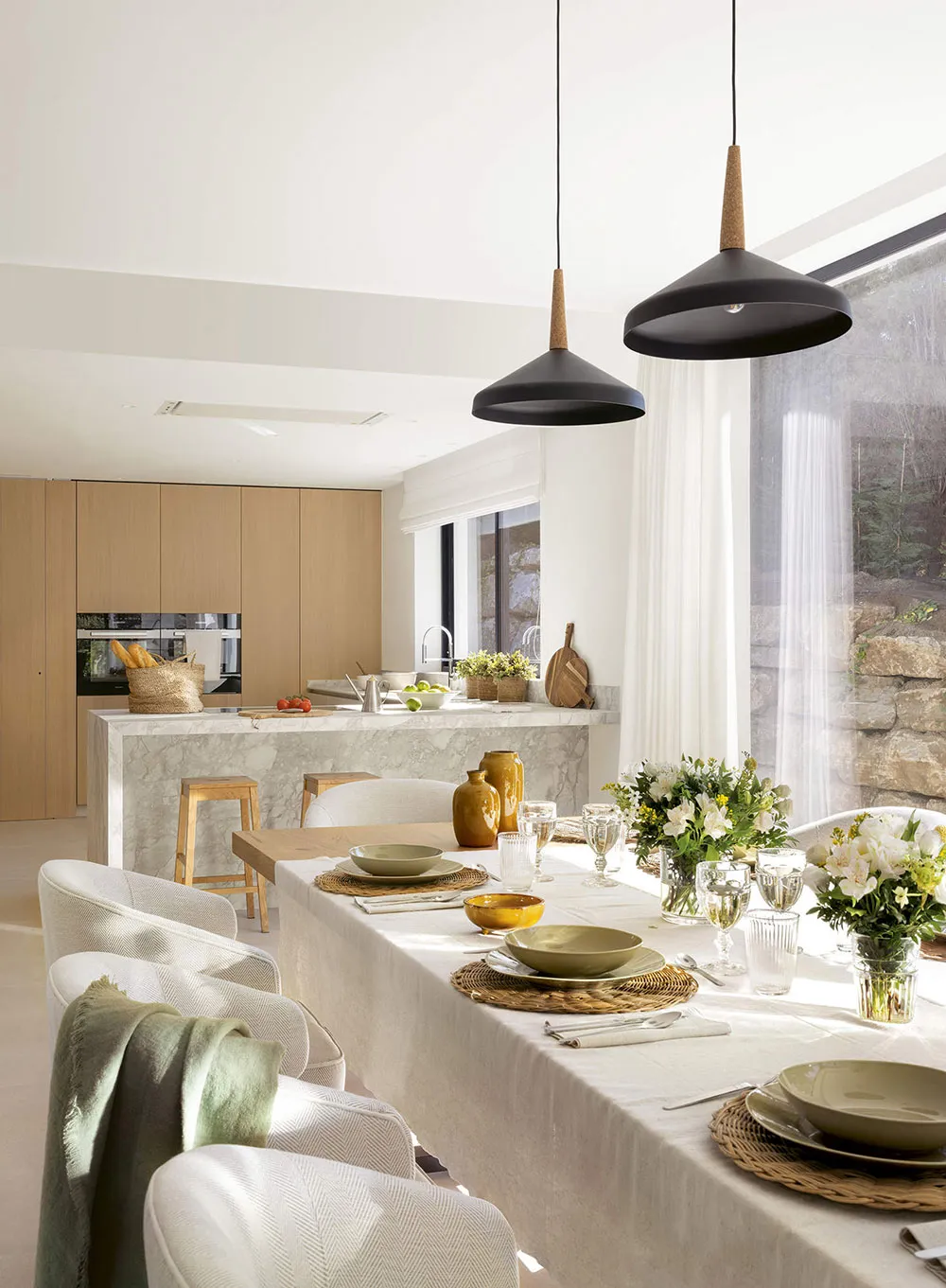 A minimalist, modern residential kitchen with a white marble countertop and wooden elements.