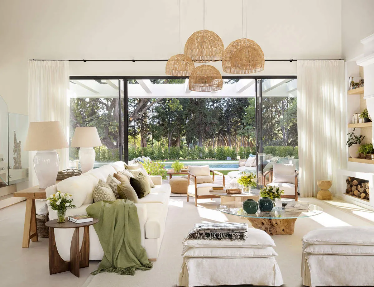 A modern living room with a white sofa, rattan pendant lights, and a glass coffee table.