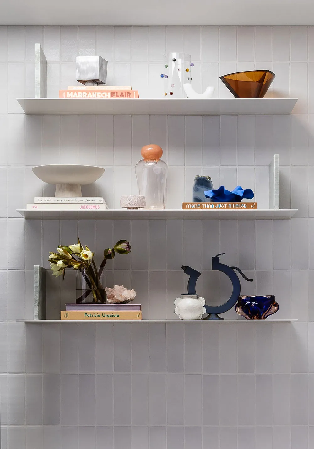 A well-organized shelf featuring ceramic, glass, and metal decorative items.