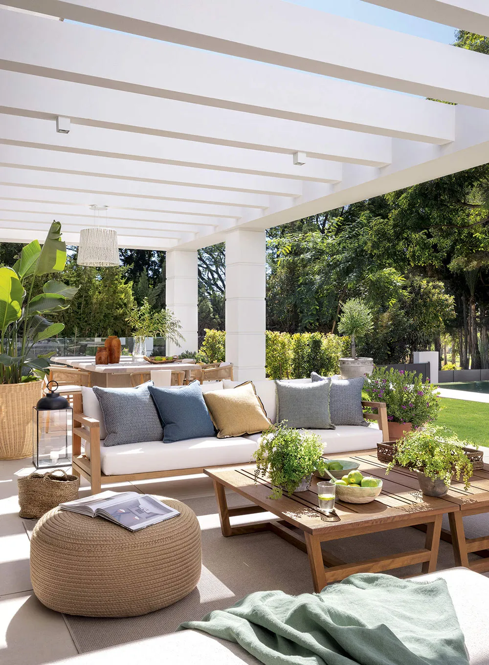 A modern outdoor space featuring a pergola, comfortable seating, and plants.