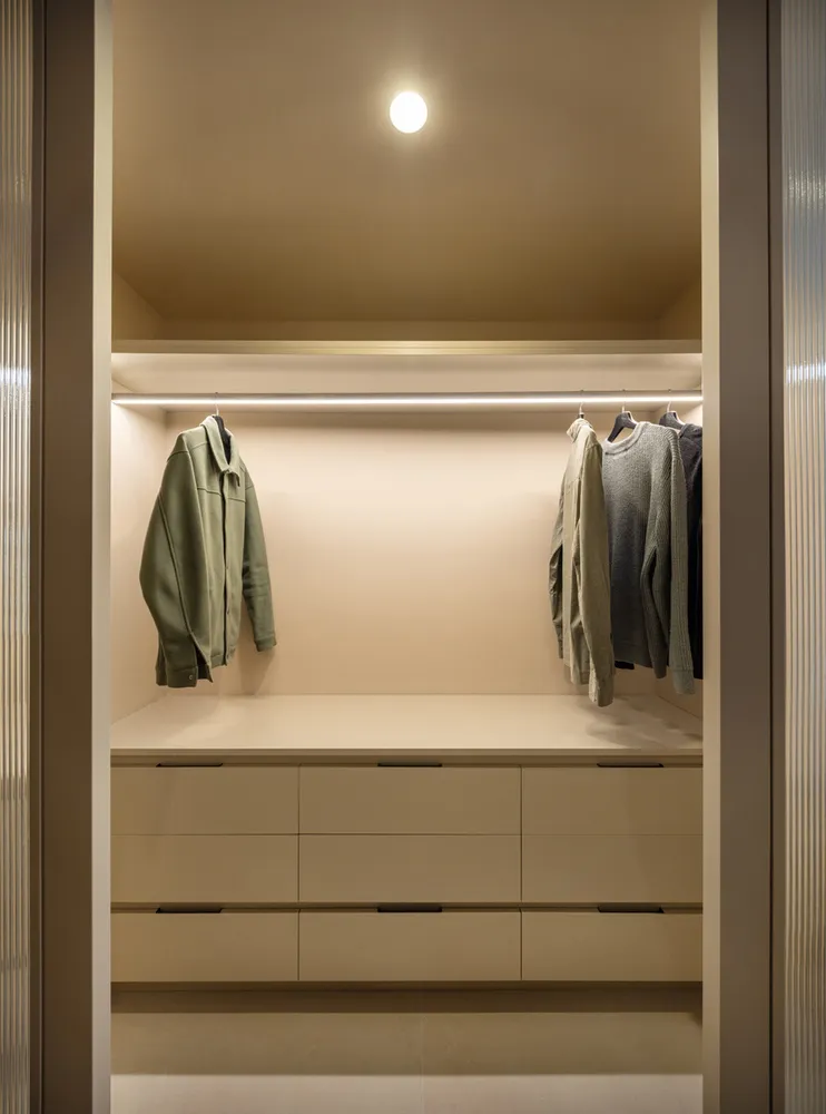 Modern closet with neutral color palette, featuring floating shelves and clothing storage.